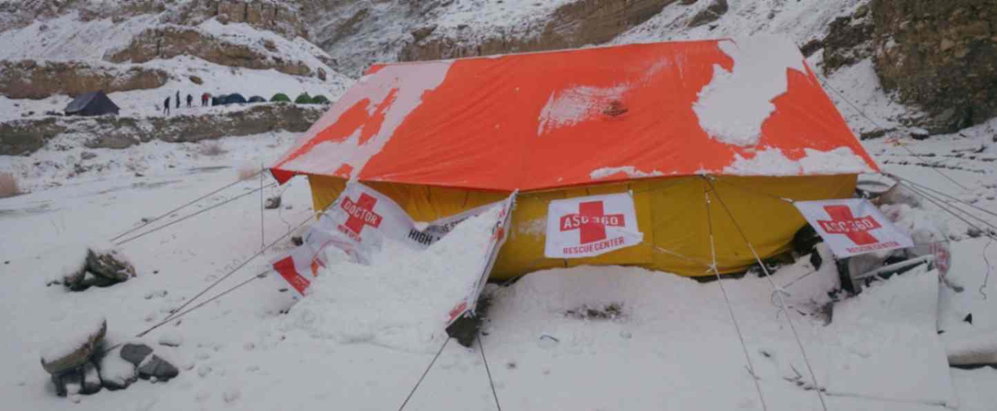 A snow-covered tent with red cross flags, representing a first aid boot camp in a wintry setting.