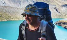 A man with a hat and backpack on a mountain, representing our esteemed partners in safe and exhilarating outdoor expeditions.